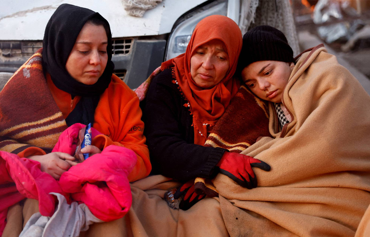 Women rest near the site of a collapsed building in Turkey, in the aftermath of the earthquakes